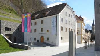 Blick auf das Liechtensteinische Landesmuseum in Vaduz mit historischen Gebäuden und bunten Fahnen