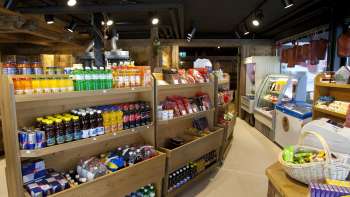 Innenansicht des Malbuner Läderli mit Holzregalen voller regionaler Produkte, Getränke und Snacks.