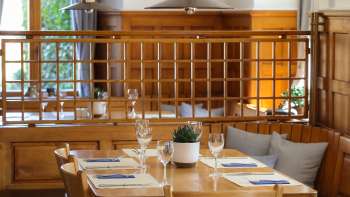 Gemütlicher Holztisch im Restaurant Rössle mit eingedecktem Gedeck und Kissenbank.
