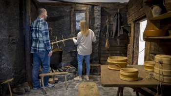 Besucher erkunden eine alte Rauchküche im Walsermuseum Triesenberg