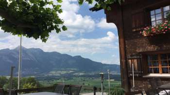 Traditionelles Gebäude mit sonniger Terrasse und Bergpanorama im Hintergrund