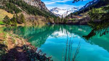 Kristallklarer Bergsee Gänglesee in Steg, Liechtenstein – eingerahmt von Wäldern, Bergen und frischem Frühlingsgrün