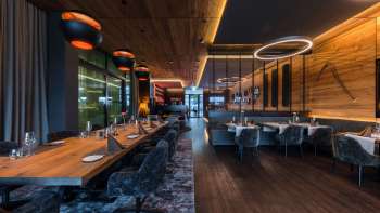 Eleganter Gastraum mit modernen Lichtelementen und Holzverkleidungen an den Wänden.