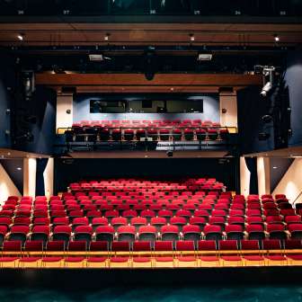 Blick von der Bühne auf rote Sitzreihen und Lichttechnik im modernen Zuschauerraum des TAK Theater Liechtenstein