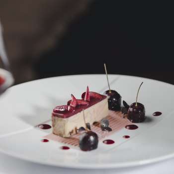 Elegante Nachspeise auf einem weissen Teller, dekoriert mit Kirschen und Schokolade