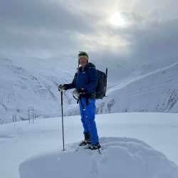 Schneeschuhwanderung mit Wanderführer Nikolaus Büchel Nikolaus Büchel steht bei Schneeschuhwanderung in winterlicher Hochgebirgslandschaft mit Rucksack und Stöcken