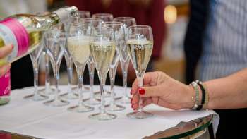Mehrere Champagnergläser werden auf einem weissen Tuch gefüllt