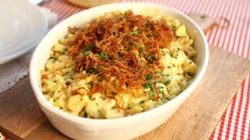 Traditionelle Käsknöpfle mit Röstzwiebeln – serviert in einem Teller auf einem Holzbrett