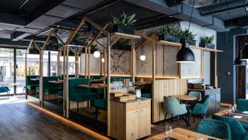 Modernes Restaurant mit stilvoller Holzkonstruktion und grünen Polstersitzen