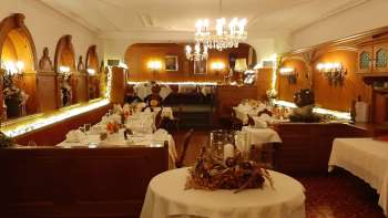 Langgestreckter Saal mit festlich gedeckten Tischen, eleganter Dekoration und warmem Licht Langgestreckter Saal mit festlich gedeckten Tischen, eleganter Dekoration und warmem Licht