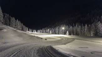 Beleuchtete Langlaufloipe in Steg bei Nacht, eingebettet in verschneite Wälder