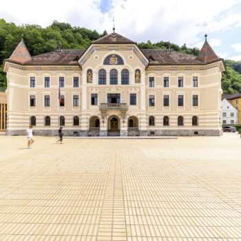 Regierungsgebäude Vaduz mit heller Fassade und Platz davor.
