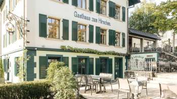 Einladende Terrasse mit Holztischen und -stühlen vor dem Gasthaus zum Hirschen