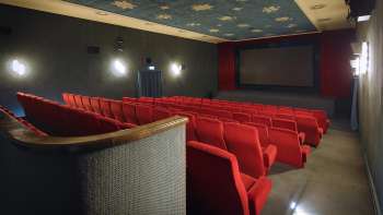 Seitlicher Blick in den Kinosaal des Alten Kino Vaduz mit roten Sesseln und atmosphärischer Beleuchtung.
