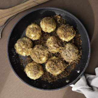 Frisch gebratene Zwetschgenknödel in Butterbröseln – liechtensteinische Mehlspeise in der Pfanne serviert