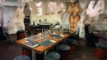 Nahaufnahme eines gemütlich eingerichteten Restaurants mit Holztischen und Stühlen, dekoriert mit Blumen und Kerzen