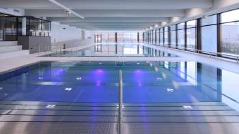 Modernes Hallenbad in Triesen mit beleuchtetem Schwimmbecken und großzügiger Glasfront.