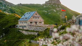 Nahaufnahme der Pfälzerhütte mit Liechtenstein-Flagge bei Abendstimmung.