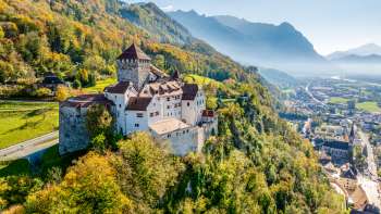 Schloss Vaduz vor herbstlicher Alpenkulisse mit Blick über das Rheintal