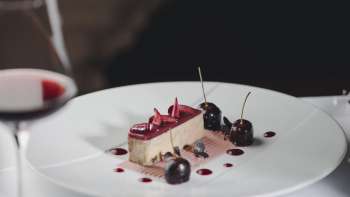 Elegante Nachspeise auf einem weissen Teller, dekoriert mit Kirschen und Schokolade