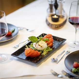 Frischer Tomaten-Mozzarella-Salat mit Rotwein auf gedecktem Tisch im JUFA Hotel Malbun