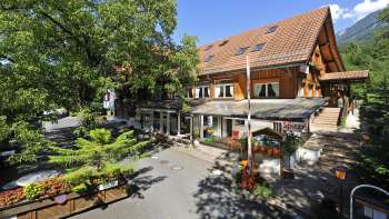 Außenansicht des Haupthauses des Campingplatzes Mittagsspitze mit Restaurant und schattiger Terrasse.