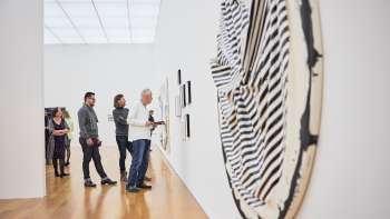 Besuchergruppe im Ausstellungsraum des Kunstmuseums, im Vordergrund ein grosses, rundes Kunstwerk