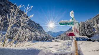 Verschneite Wegweiser und traumhafte Winterlandschaft bei strahlendem Sonnenschein in Steg, Liechtenstein.