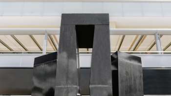 Skulptur „Progression einer Form in 3 Stelen“ von Christian Megert aus schwarzem Stein vor moderner Glasfassade in Vaduz.