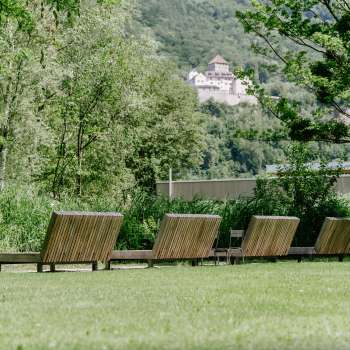 Wiese mit Liegen aus Holz mit Blick auf das Schloss Vaduz