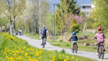 Familie radelt auf dem Frühlingsradweg im Naturpark Haberfeld, umgeben von blühenden Wiesen und Bäumen.