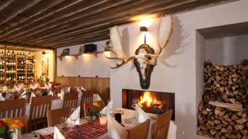 Gemütliches Restaurantambiente mit rustikalen Holzbalken und Kamin