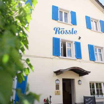 Außenansicht des Restaurant Rössle mit blauen Fensterläden und gemütlichem Eingangsbereich.