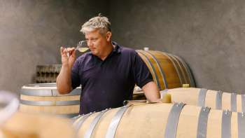 Winzer vom Weingut Hoop in Liechtenstein beim Verkosten des Weins direkt aus dem Holzfass im Weinkeller.