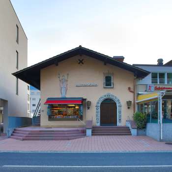 Außenansicht des Alten Kino Vaduz mit Schriftzug über dem Eingang und roten Markisen, zwischen zwei modernen Gebäuden gelegen.