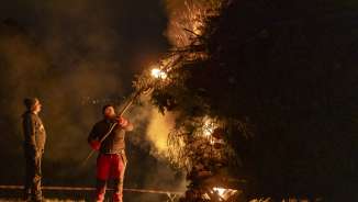 Zwei Männer entzünden in der Nacht ein grosses Funkenfeuer beim traditionellen Funkensonntag in Liechtenstein.