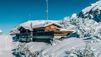 Eine Frau geniesst die Aussicht von der Aussichtsterrasse Sareis auf die Liechtensteiner Alpen und das Rheintal bei klarem Wetter