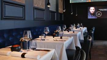 Eleganter Innenbereich des Esquire Bar & Bistro in Vaduz mit stilvoll gedeckten Tischen, dunkelblauer Polsterbank und stimmungsvollem Licht.