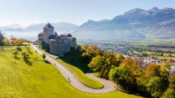 Schloss Vaduz auf einem Hügel mit Blick auf das Rheintal und umliegende Berge.