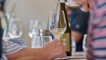 Ein Glas Weißwein wird während einer geführten Verkostung eingeschenkt.