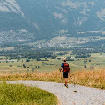 Liechtenstein-Weg Etappe Schaanwald–Ruggell Wanderer auf dem Liechtenstein-Weg zwischen Schaanwald und Ruggell mit Blick auf das weite Rheintal und das Alpenpanorama.