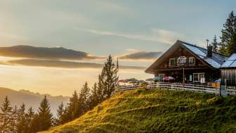 Gafadurahütte im Abendlicht – idyllische Berghütte mit Aussicht in Liechtenstein Gafadurahütte auf grüner Anhöhe in Liechtenstein bei Sonnenuntergang mit Panoramablick über die Berge
