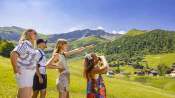 Familie schaut in die Ferne in der alpinen Landschaft mit Blick auf die Berge im Sommer Familie schaut in die Ferne in der alpinen Landschaft mit Blick auf die Berge im Sommer