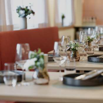 Nahaufnahme stilvoll gedeckter Tische im RUUF Restaurant mit dunklem Geschirr und Blumenvasen
