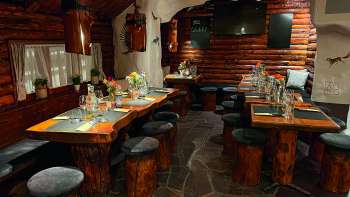 Blick auf ein rustikal eingerichtetes Restaurant mit Holzmöbeln, grün dekorierten Tischen und Kerzen.
