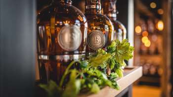 Flaschen mit frisch gezapftem Bier auf sonnendurchfluteter Terrasse, umgeben von lebendiger Stimmung