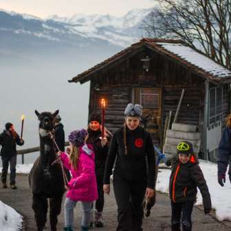 Lamatrekking mit Fackeln im Winter Familienfreundliches Lamatrekking bei Schnee in Liechtenstein mit Fackeln und Blick auf die Berge – ein besonderes Outdoor-Fondueerlebnis.