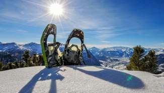 Zwei Schneeschuhe im verschneiten Malbun vor Panoramablick auf die Alpen am Alpspitz in Liechtenstein bei strahlendem Sonnenschein