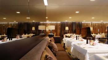 Elegantes Restaurant mit gespiegelt gedeckten Tischen und gedämpfter Beleuchtung