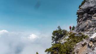 Wanderer auf dem schmalen Fürstensteig in Liechtenstein mit Blick auf die Wolken unterhalb des Pfads